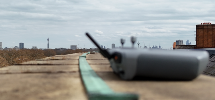 UAV controller positioned on the Royal Albert Hall roof during an inspection survey, with lightning conductor tape and the London skyline visible in the background.