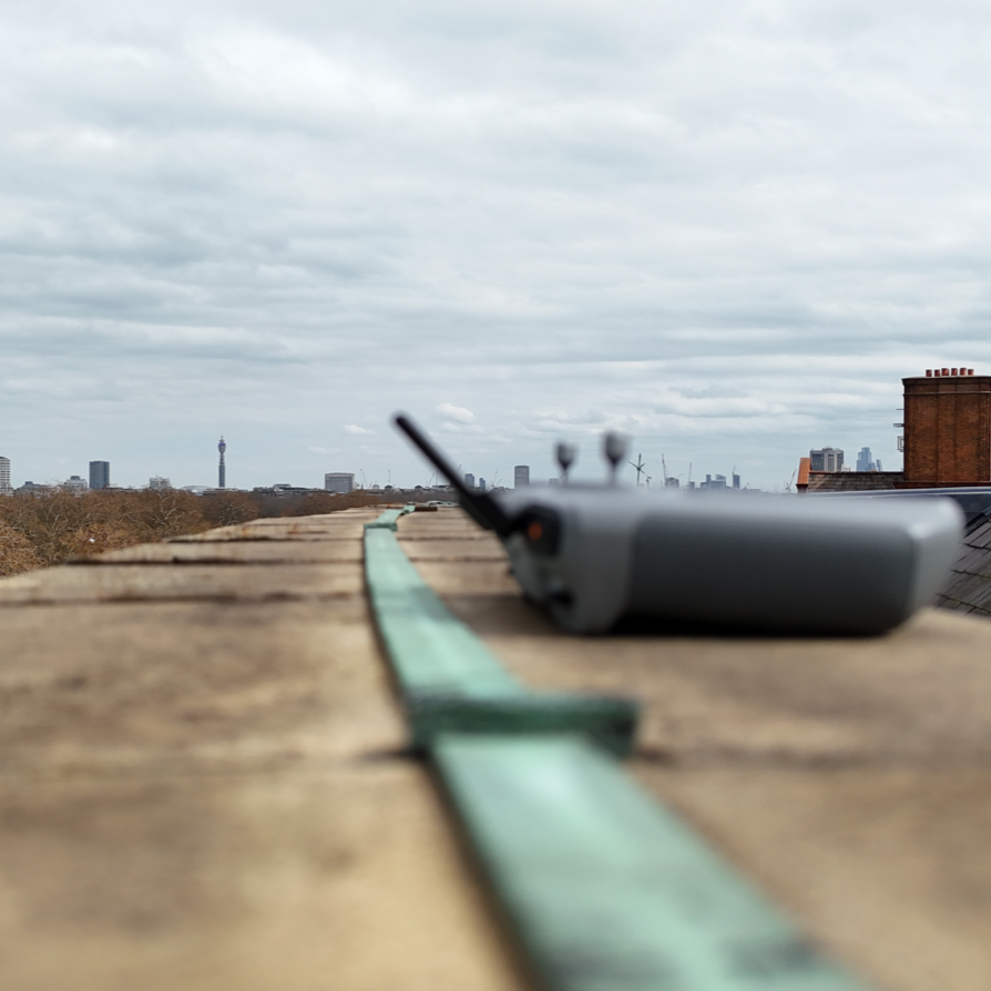 UAV controller positioned on the Royal Albert Hall roof during an inspection survey, with lightning conductor tape and the London skyline visible in the background.