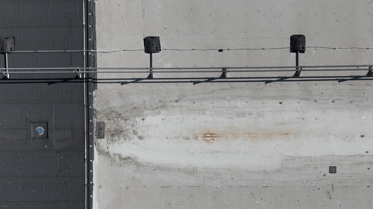 Close aerial view of flat roof coverings, drainage outlet and roof fixtures captured for condition assessment.