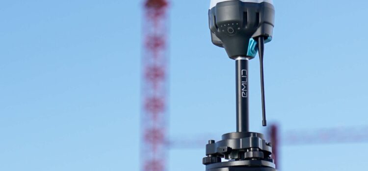 GNSS receiver mounted on a tripod at a construction site with a tower crane in the background.