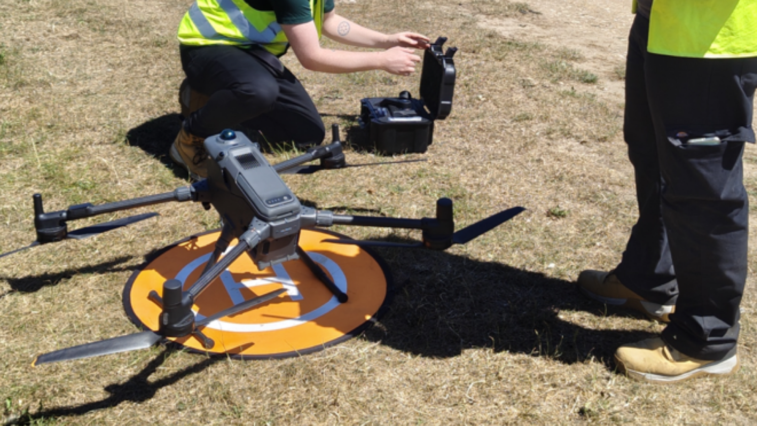 Survey operatives preparing a DJI Matrice 400 RTK drone for a mapping survey in the field.